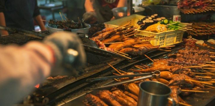 street-food-stall-with-many-skewers-grilling-over-open-heat-and-hands-preparing-food-2